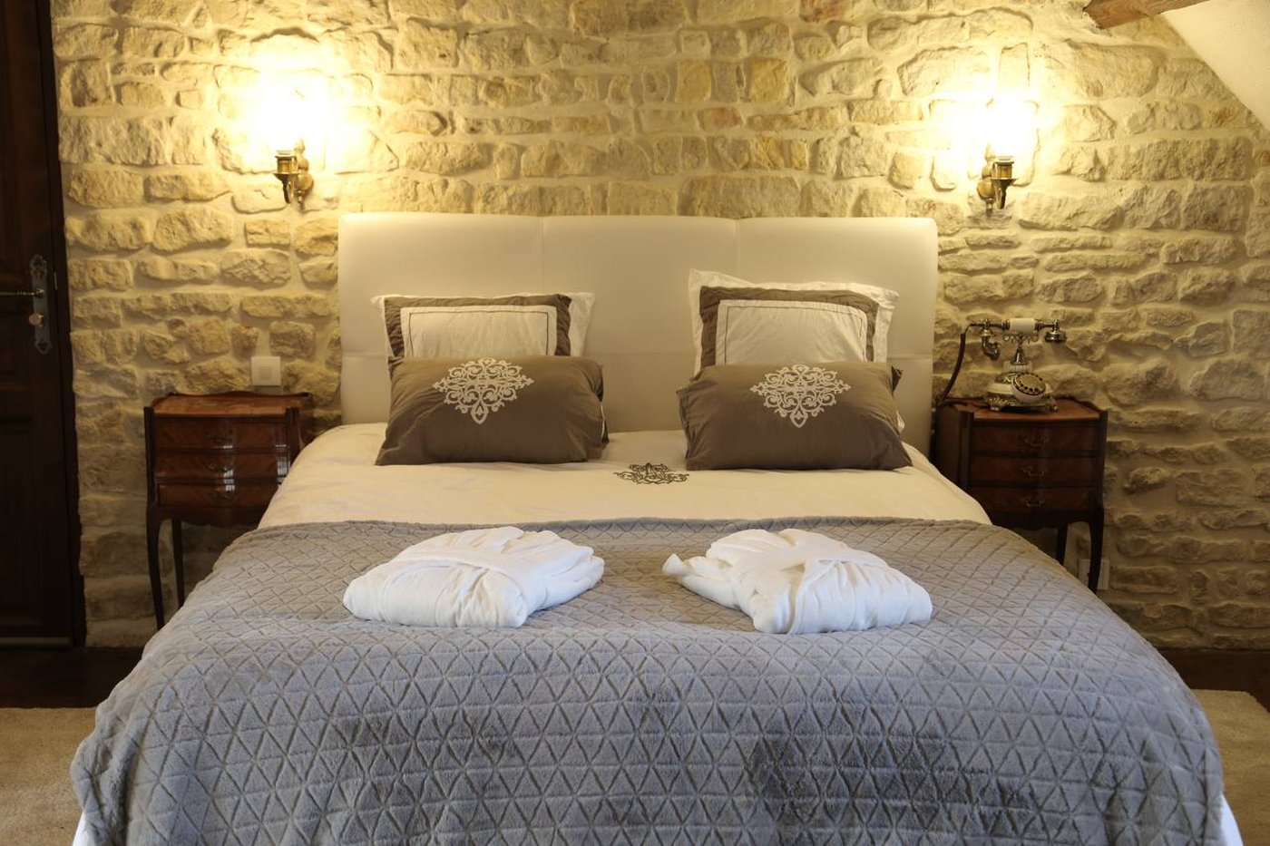 Chambre Supérieure — le lit, murs de pierre et appliques