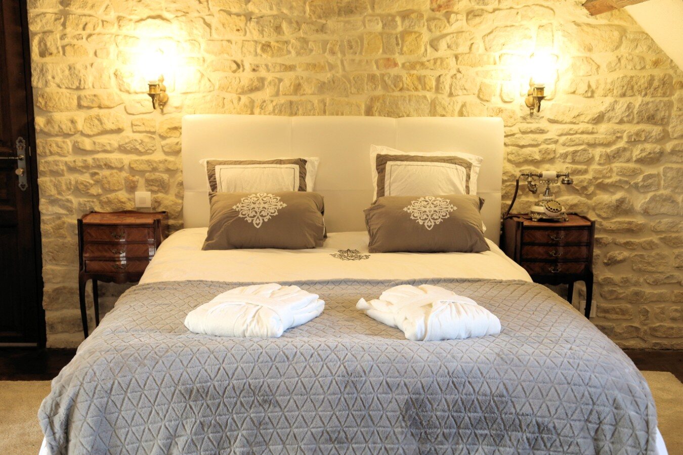 Chambre aux murs de pierre et lit douillet