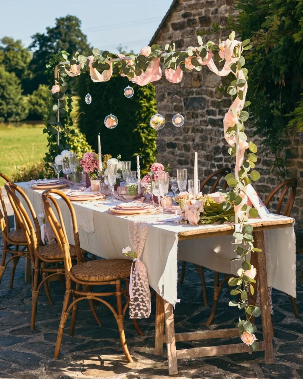 La table dressée dehors, sous les guirlandes roses