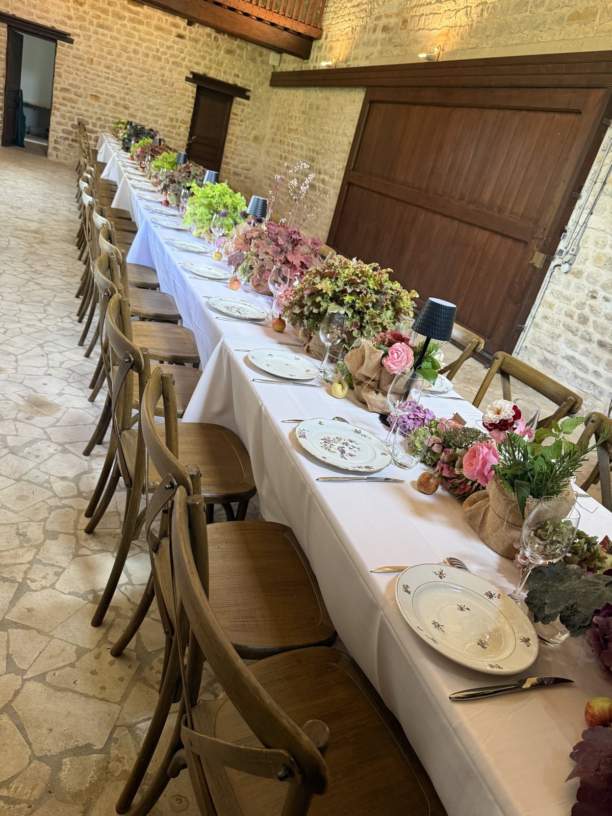La longue table dressée, ses bouquets roses et son feuillage
